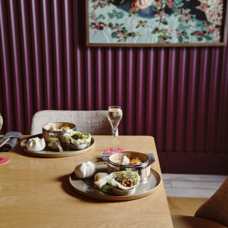 Plates of Asian-style shared dishes and champagne set on a table in a restaurant setting