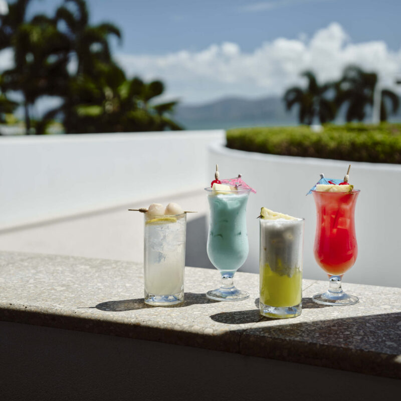 Colourful birthday cocktails served on a sunlit terrace with tropical views